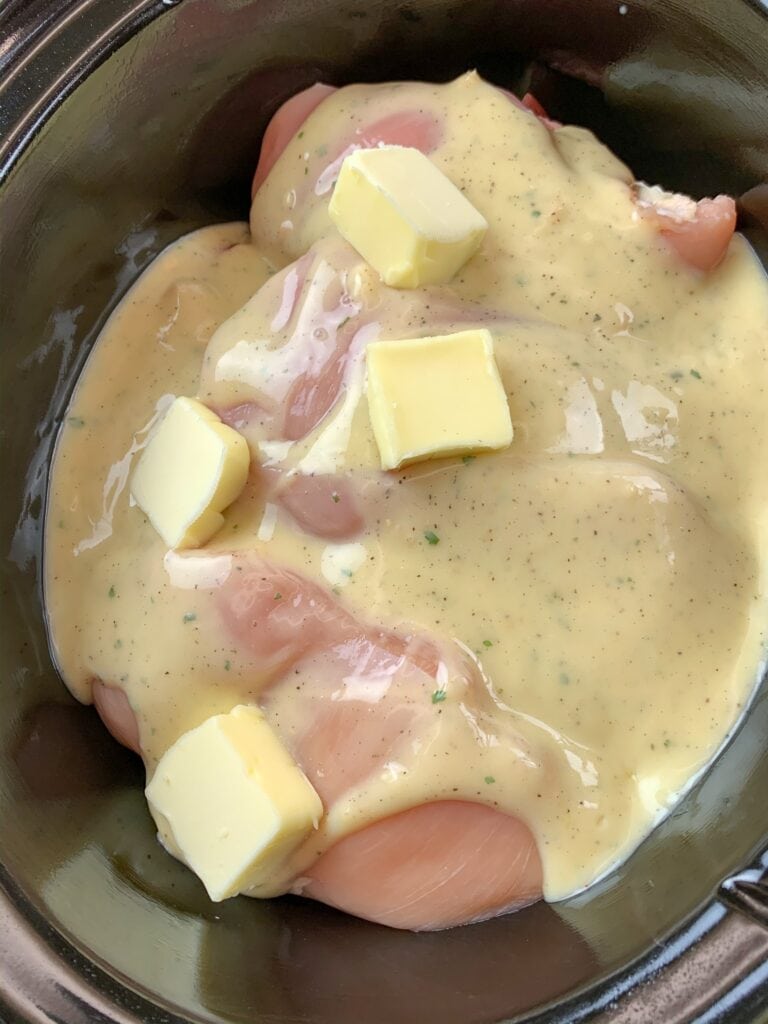 Potatoes, creamy ranch sauce, chicken, and butter in a slow cooker. 