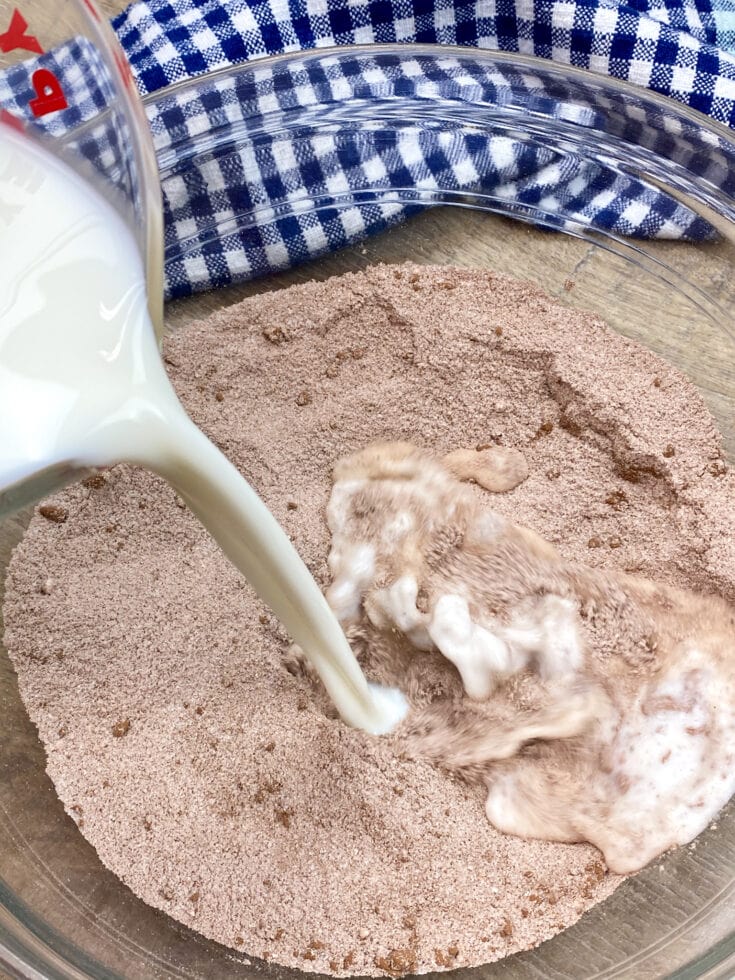 Pouring milk into a bowl with cocoa, flour, and sugar.