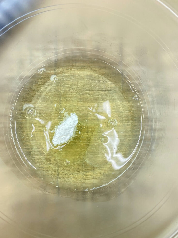 Egg whites and cream of tartar in a glass bowl. 