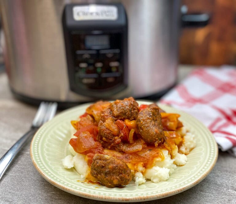 Pork sausage on a plate with veggies and mashed potatoes.