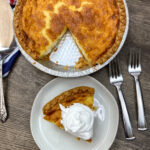 A slice of buttermilk pie on a white plate with whipped topping.