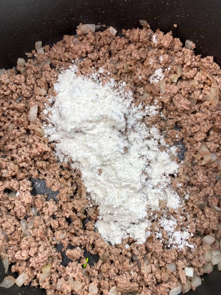 Cooked ground beef and flour in a skillet.