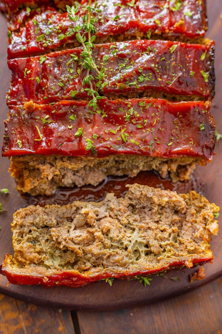 Sliced meatloaf on a cutting board with ketchup on top.