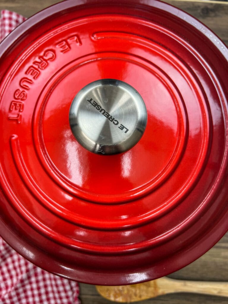 Adding the red lid on the saucepan while the casserole cooks