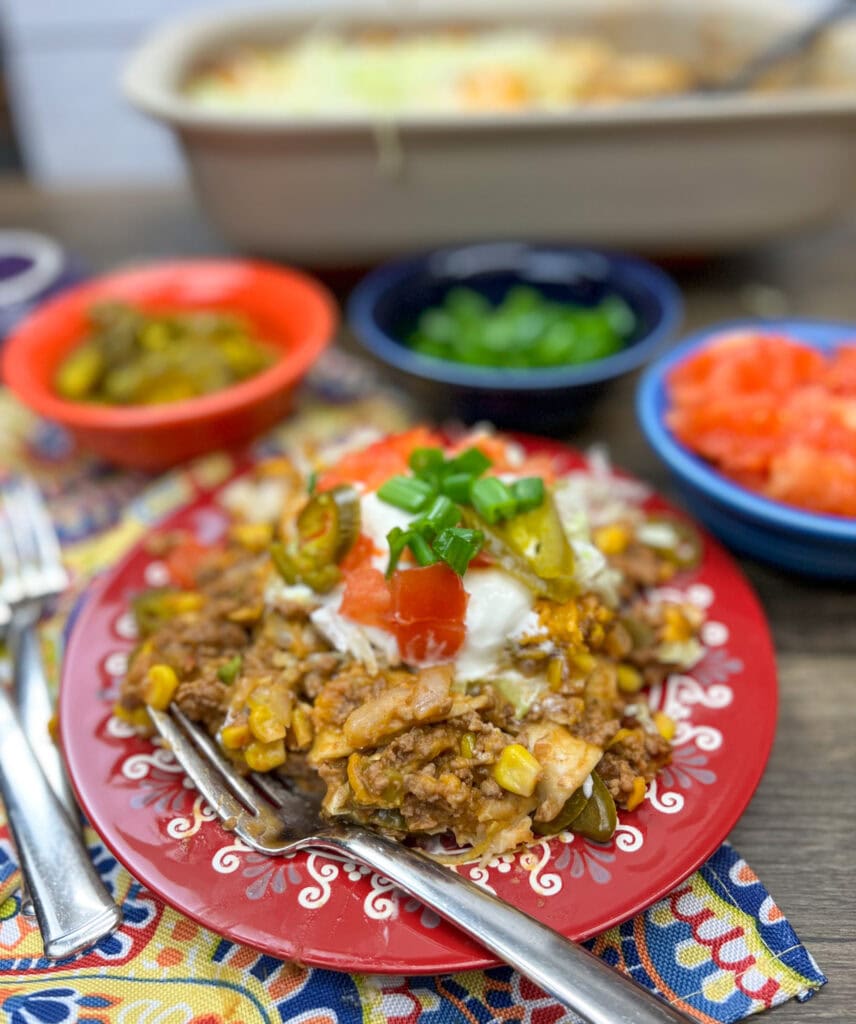 Mexican ground beef casserole on a red plate with a fork.