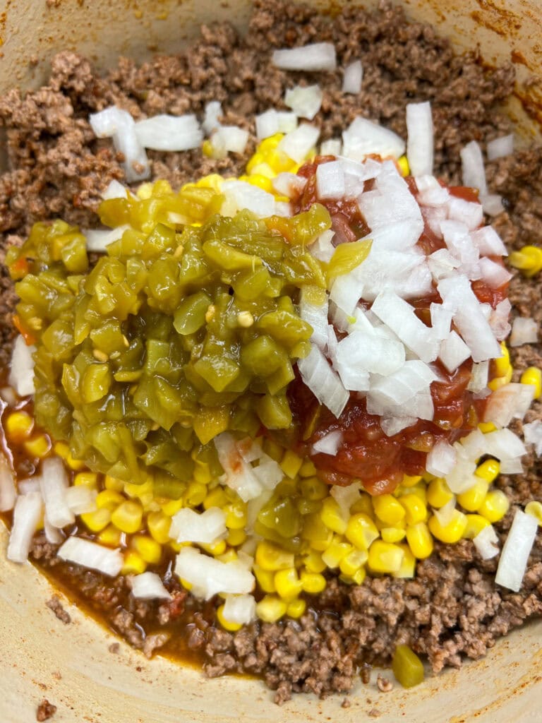 Green chiles, diced white onions, and ground beef in a large saucepan.