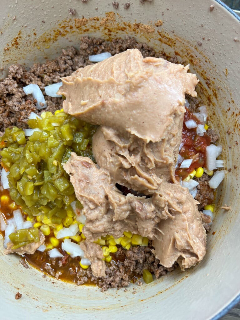 Refried beans in a pot with ground beef.