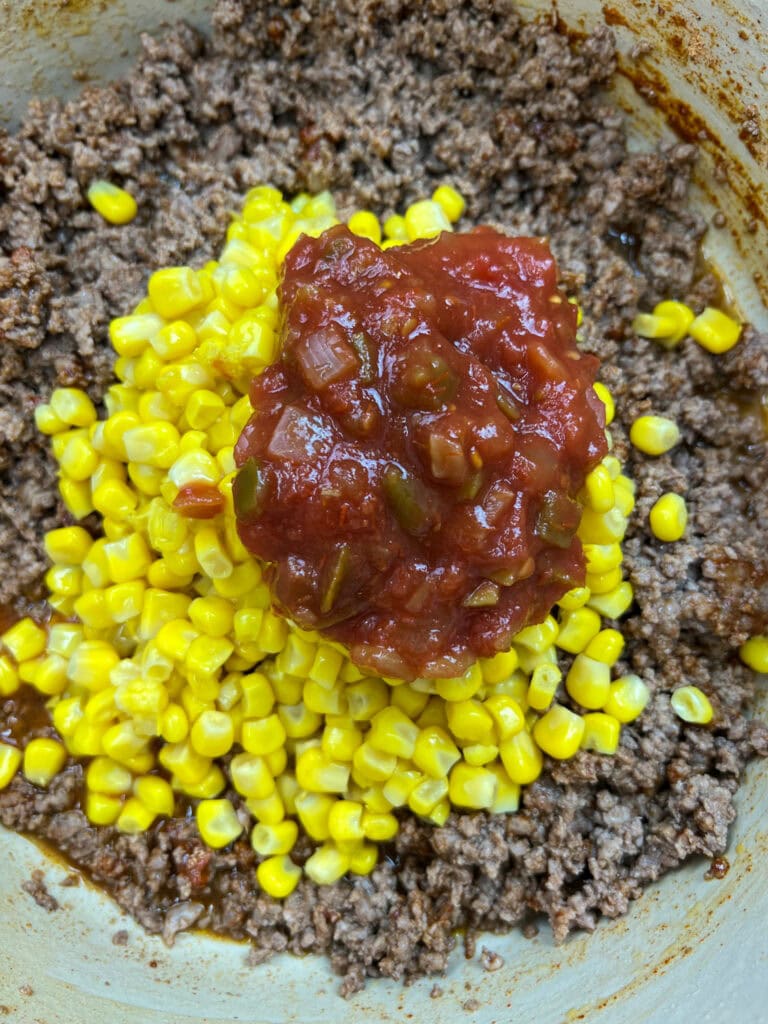 Adding salsa and corn to the pan with ground beef