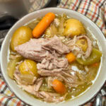 slow cooker pork roast with vegetables in a brown bowl.