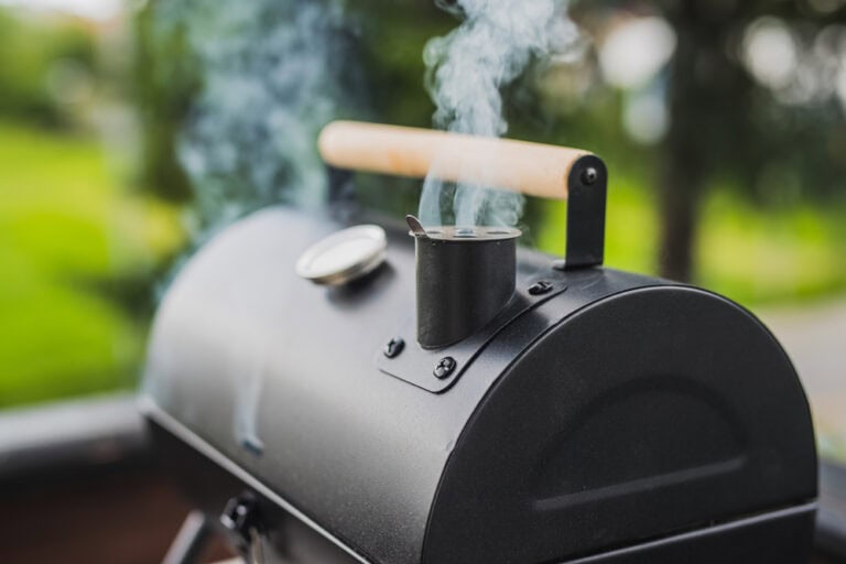 Barbecue smoker. There is smoke coming out of the black smoker.