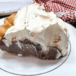 A slice of chocolate cream pie with whipped topping.