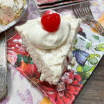 A slice of millionaire pie with whipped cream on top and a cherry.