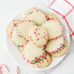 Sliced sugar cookies stacked on a white plate.