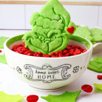 Grinch cookie in a bowl of red heart candies.