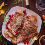 Slow cooker turkey breast on a white plate with cranberries.