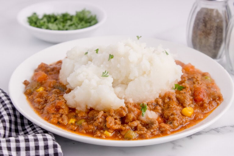 Shepherd's pie on a plate with mashed potatoes on top.