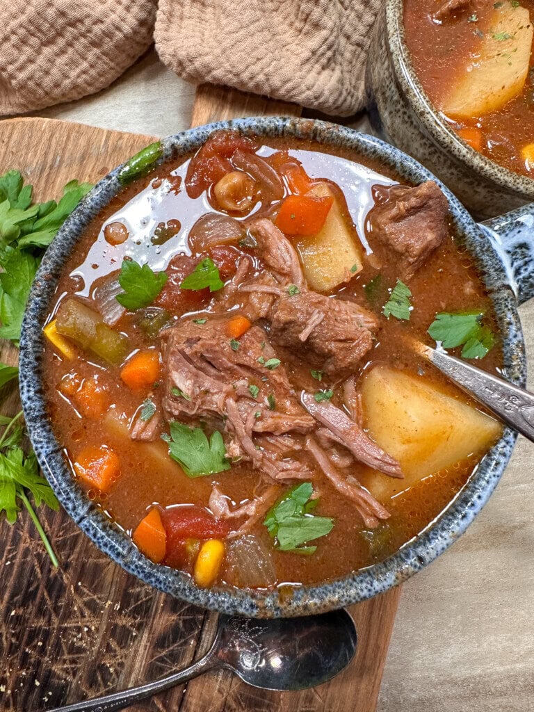 Crock Pot beef stew with potatoes and tomatoes in a soup bowl.