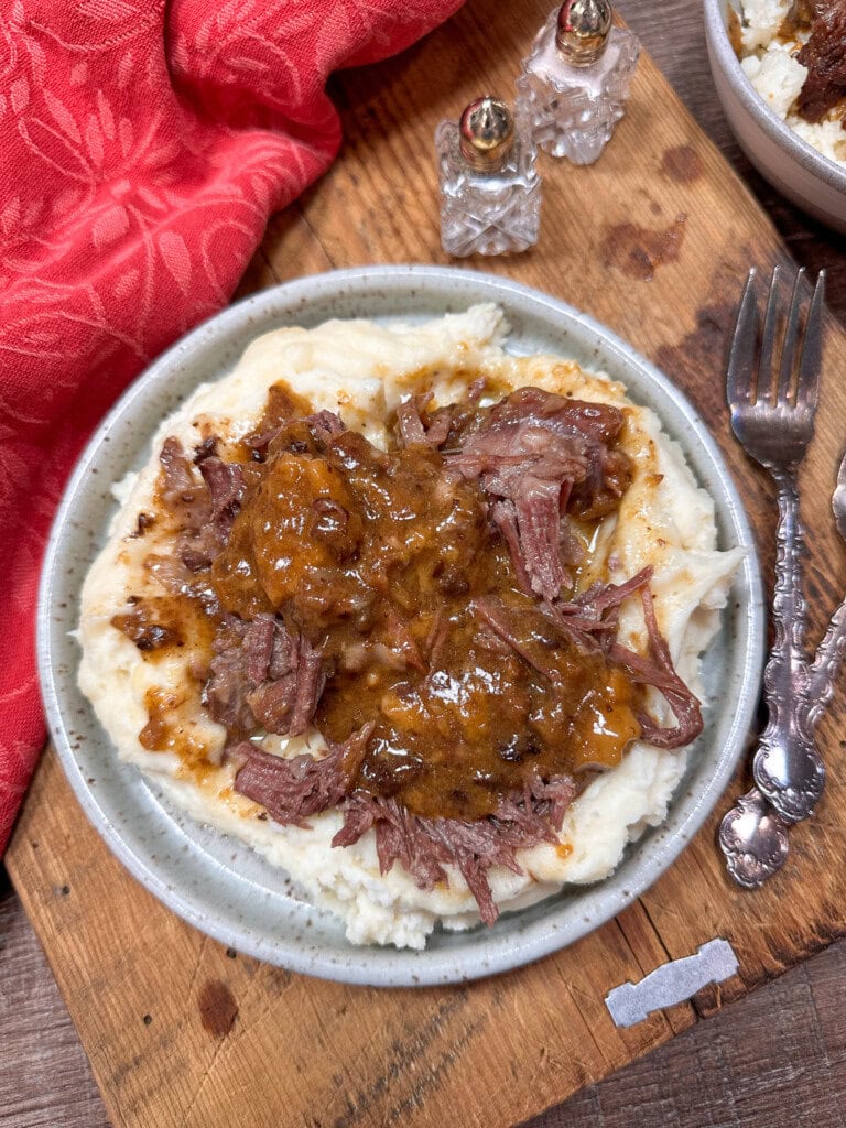 Slow cooker ginger ale pot roast on a plate. The beef is on top of mashed potatoes.