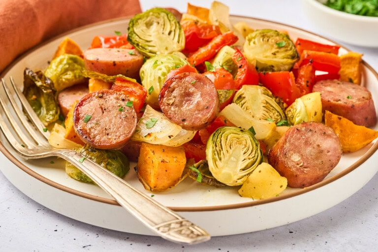 A plate of veggies, sausage, and chicken.