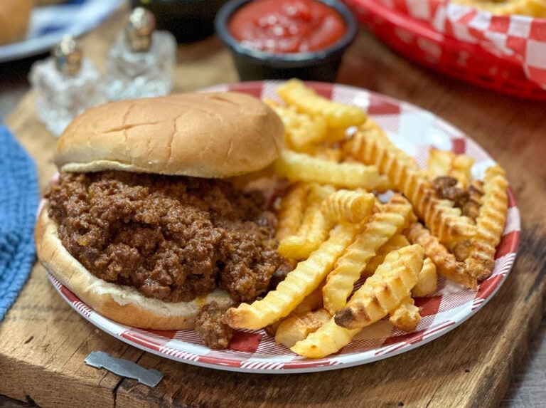 Sloppy Joes on a plate with a bun and french fries.