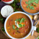 Bean soup on a cutting board next to another bowl of the soup.