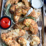 Chicken tenders on a baking sheet with ketchup and ranch dressing on the side.